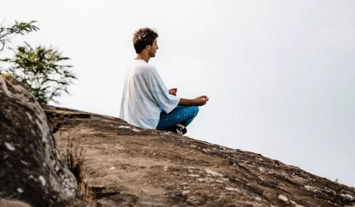 Espiritualidad: Hombre meditando, sentado en una gran piedra